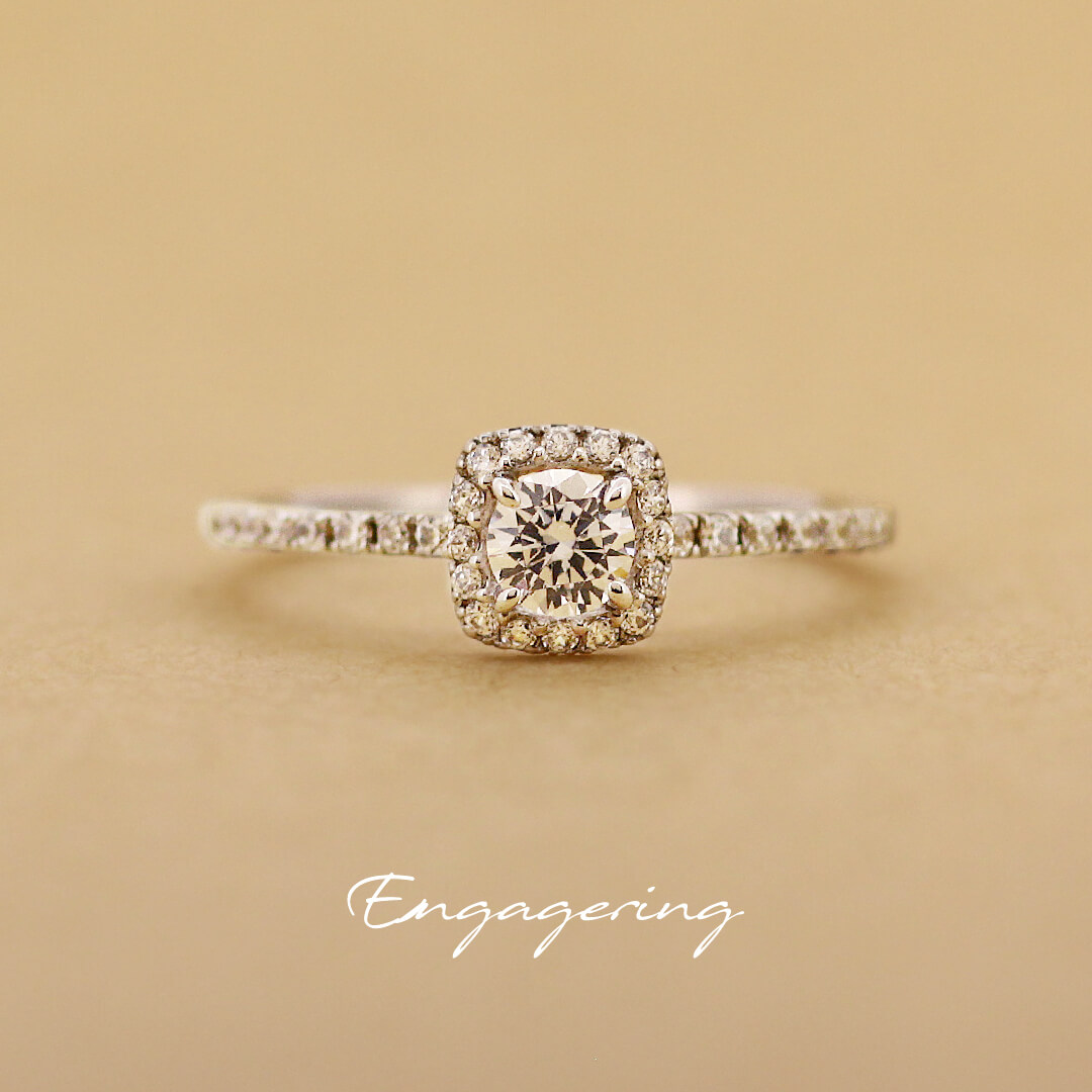 センターダイヤをメレダイヤで四角く囲み、細みのアームにもメレダイヤを並べたストレートラインの婚約指輪です。