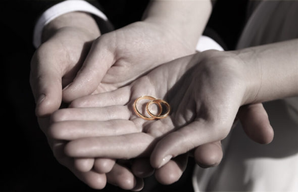 新郎新婦がふたりで大切にゴールドの指輪を持っています。