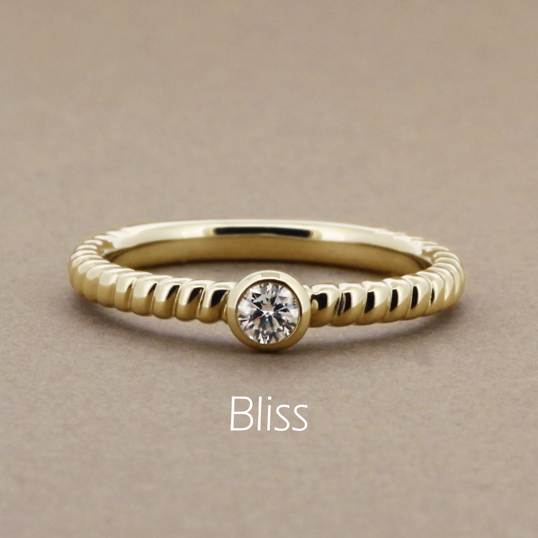 「Bliss」という名前が付いた、大きめの縄目のようなデザインアームに0.1ctのダイヤモンドをフクリンで留めたイエローゴールドの指輪。