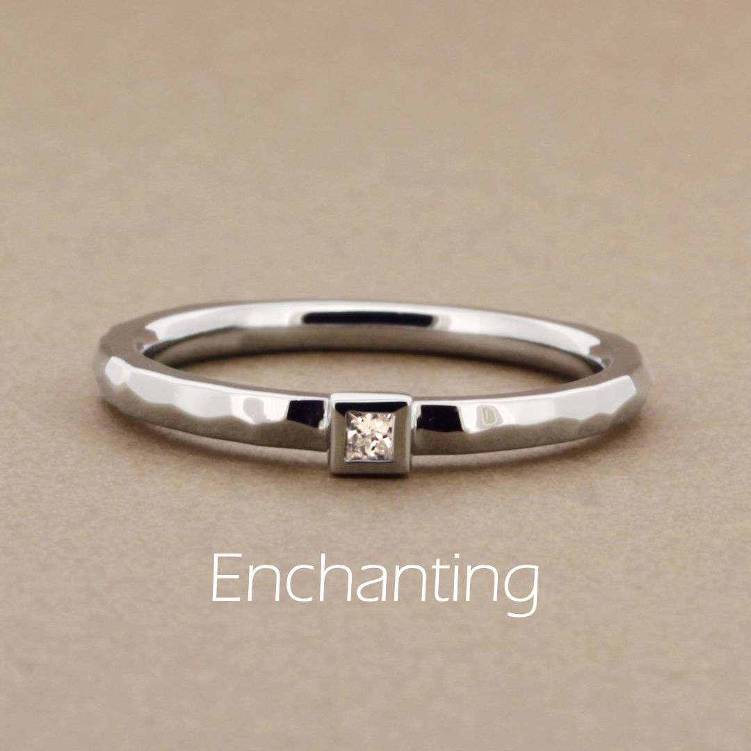 「Enchanting」という名前がついた、ランダムに槌打った個性的なアームにプリンセスカットのダイヤモンドを留めたブラックゴールドの指輪