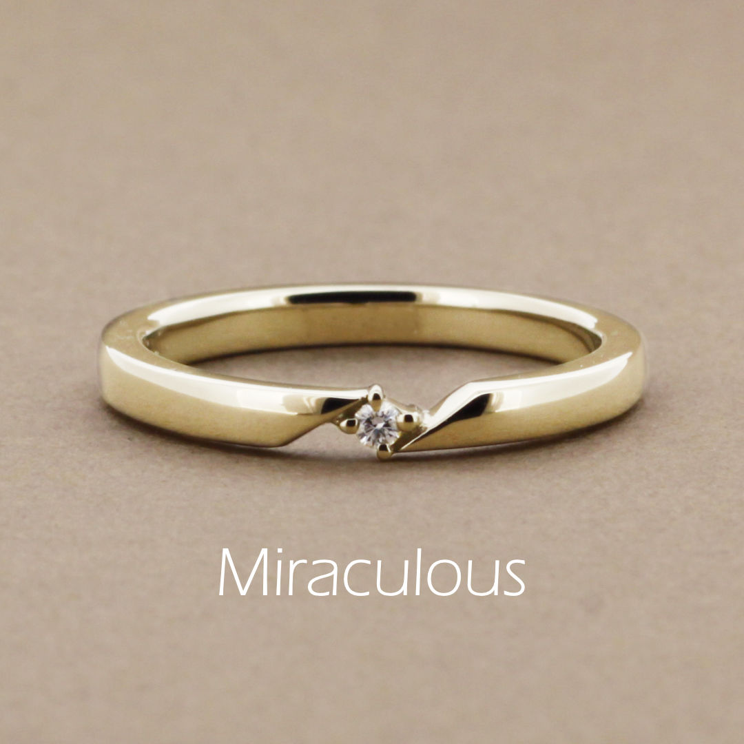 「Miraculous」という名前が付いた、ほどよいボリューム感のアームが挟み込むように小さなダイヤモンドをクロスの爪で留めたイエローゴールドの指輪