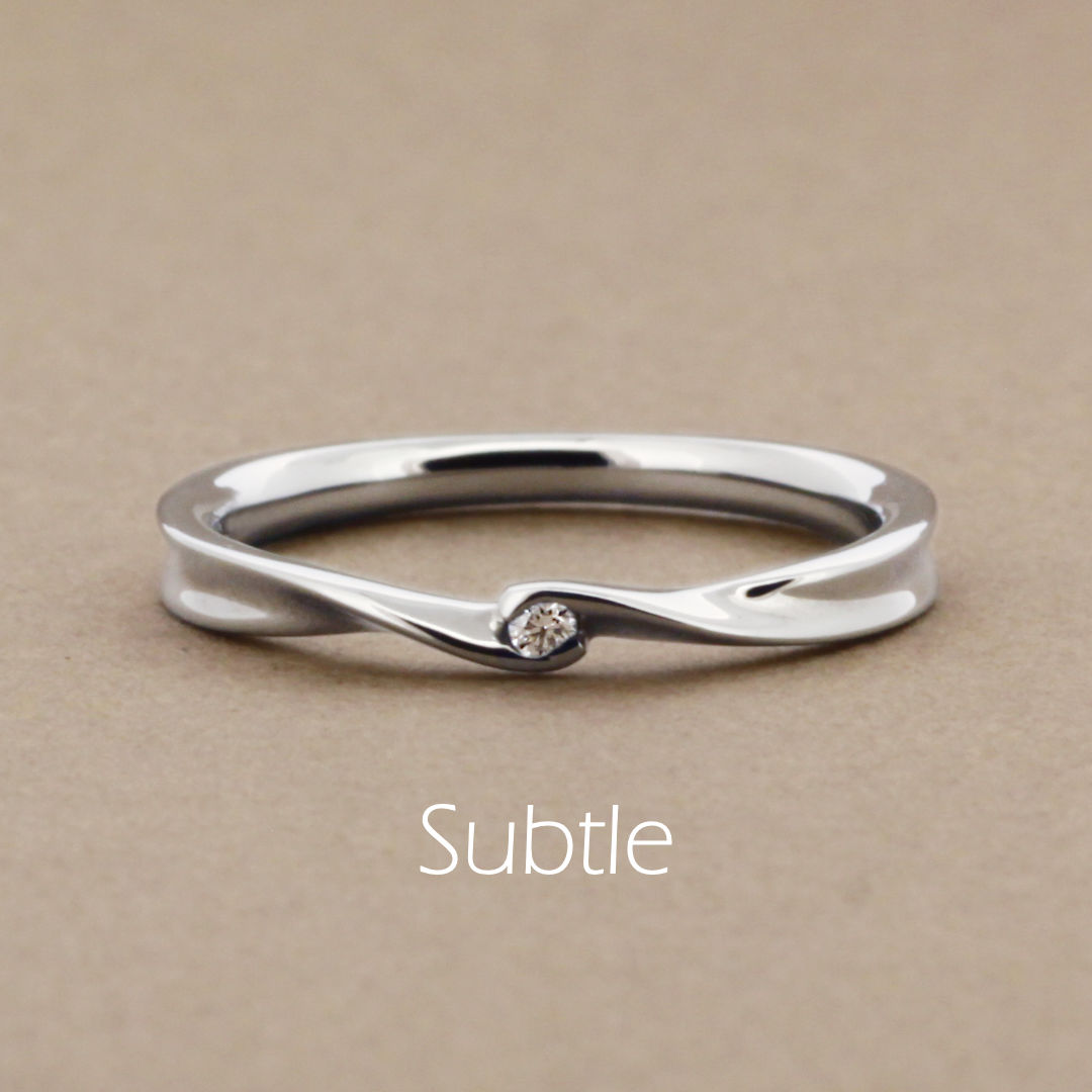 「Subtle」という名前がついた、リボンのようなひねりのあるアームに小さいダイヤを1粒留めたプラチナの指輪